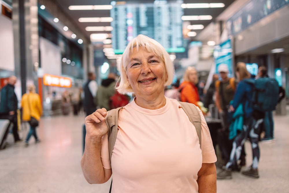 Ältere Frau mit Koffer am Flughafen