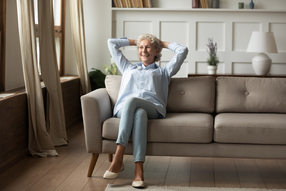 Ältere Frau sitzt alleine auf dem Sofa